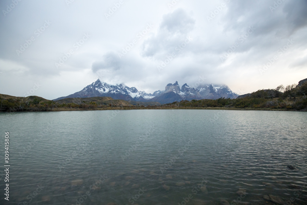 Cloudy sunrise over the Torres del Paine mountains that overlook the waters of a lake, Torres del Paine National Park, Chile