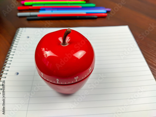 Pomodoro study technique with a kitchen timer in a shape of an apple for setting an alarm for better productivity and study sessions to beat procrastination