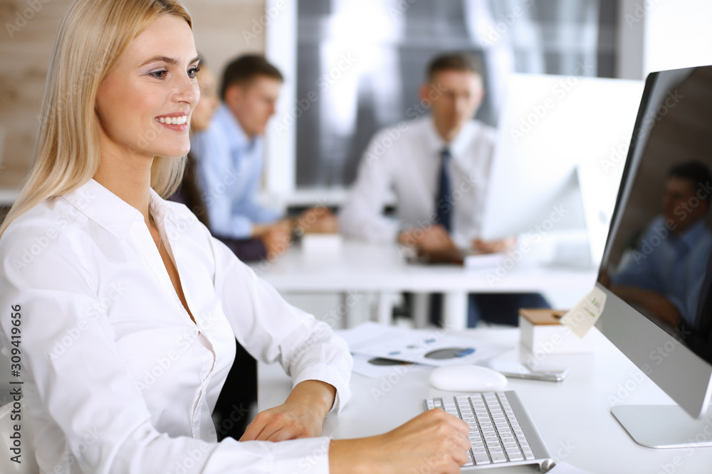 Business woman using computer at workplace in modern office. Secretary or female lawyer smiling and looks happy. Working for pleasure and success Business woman using computer at workplace in modern office. Secretary or female lawyer smiling and looks happy. Working for pleasure and success