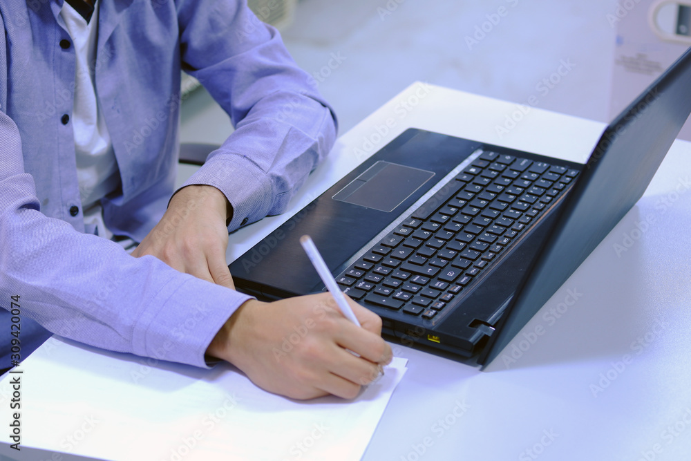 Engineer working on computer and taking some notes on a white paper Engineer working on computer and taking some notes on a white paper