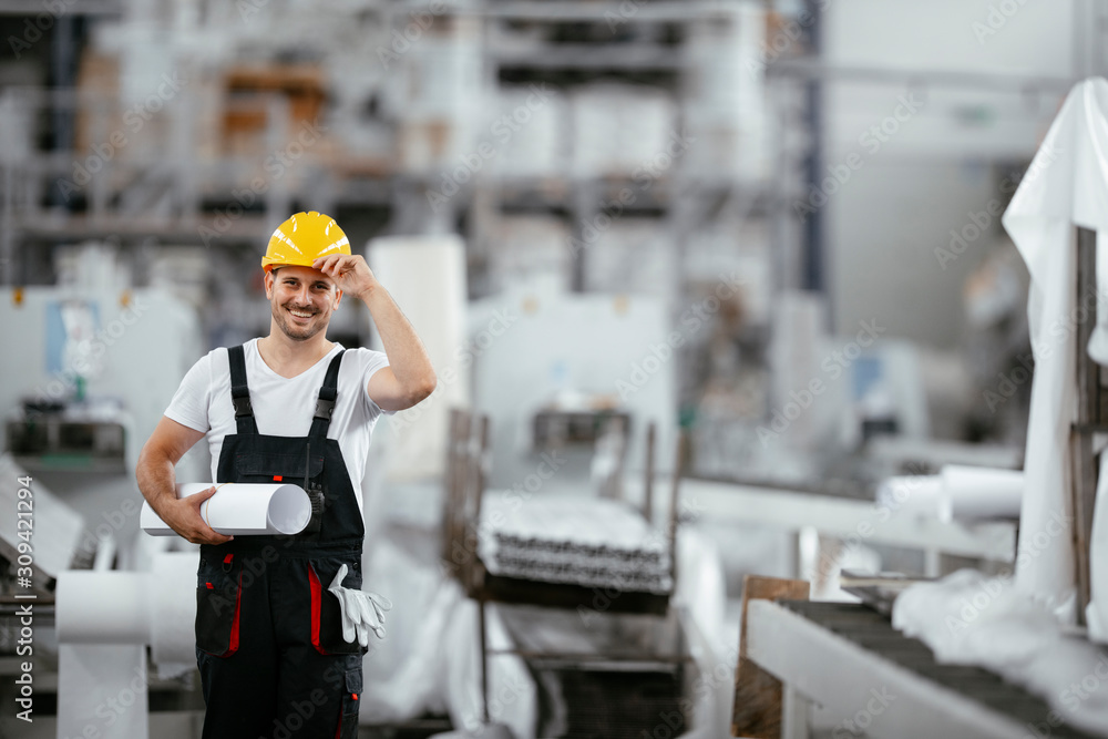 Attractive worker in uniform. Man in factory with blueprint. Attractive worker in uniform. Man in factory with blueprint.