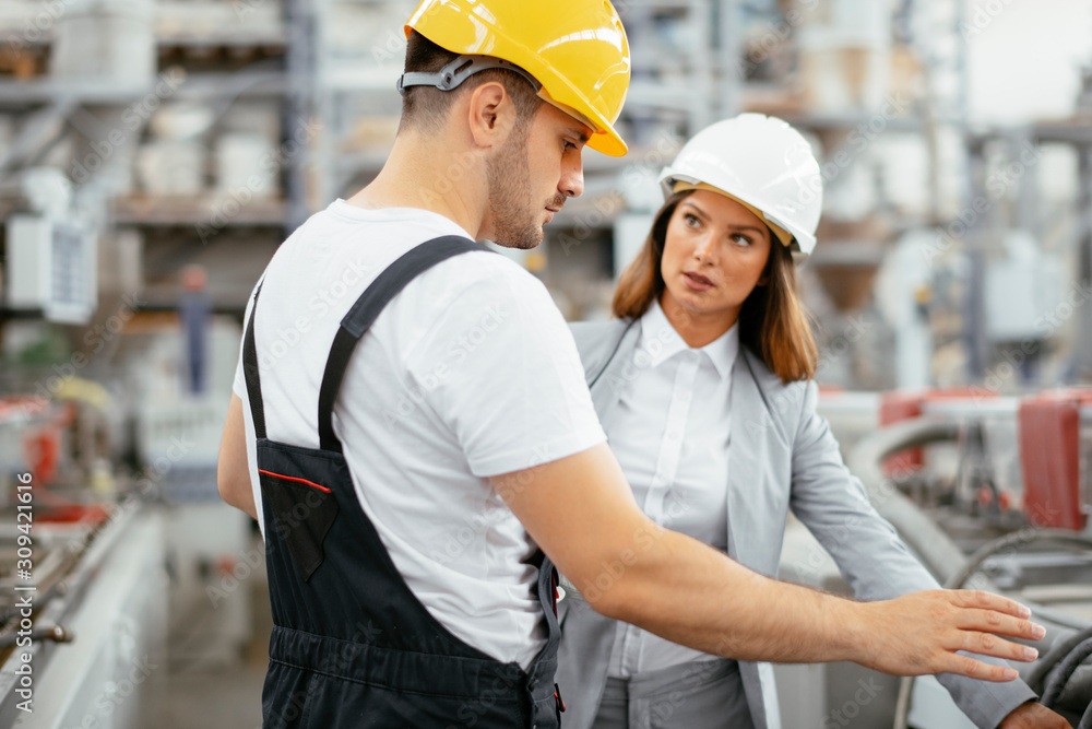 Man and woman discussing work in factory. Man and woman discussing work in factory.