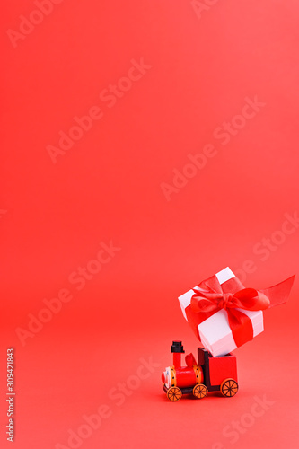 Christmas background red and selective focus. Boxes with gifts on a toy wooden train. Holiday card with Copy space.
