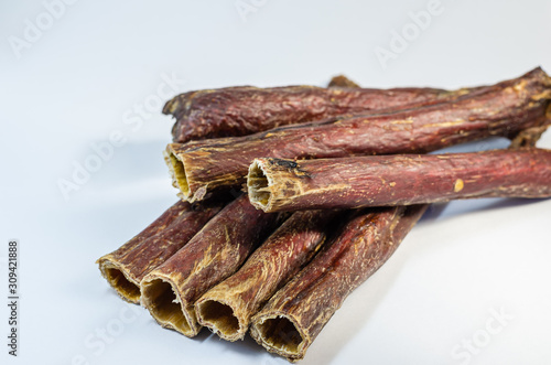 A group of sticks of a dried cow esophagus. Natural healthy treats for dogs. Beef esophagus on a light background. Tasty goodies for pets. Selective focus.