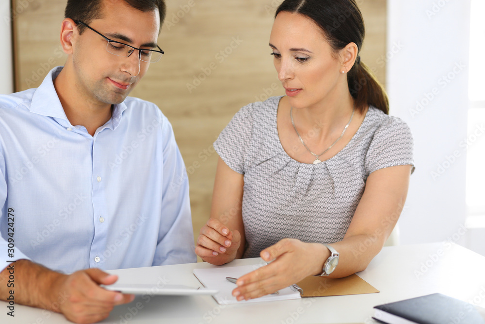 Business woman and businessman discussing questions while using a computer in modern office. Group of diverse people. Teamwork, partnership and business concept Business woman and businessman discussing questions while using a computer in modern office. Group of diverse people. Teamwork, partnership and business concept