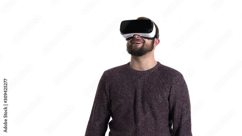 Amazed young man using virtual reality glasses. Happy guy wearing VR googles pointing at something with index finger and laughing Amazed young man using virtual reality glasses. Happy guy wearing VR googles pointing at something with index finger and laughing