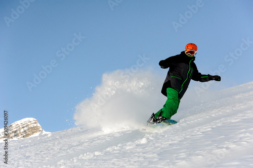 Snowboarder slides on mountain and raises up snow