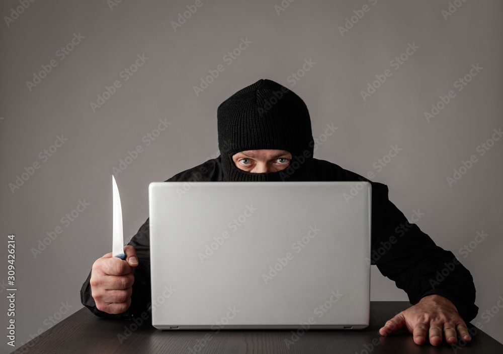 Hacker in mask using a laptop. Hacker in mask using a laptop.