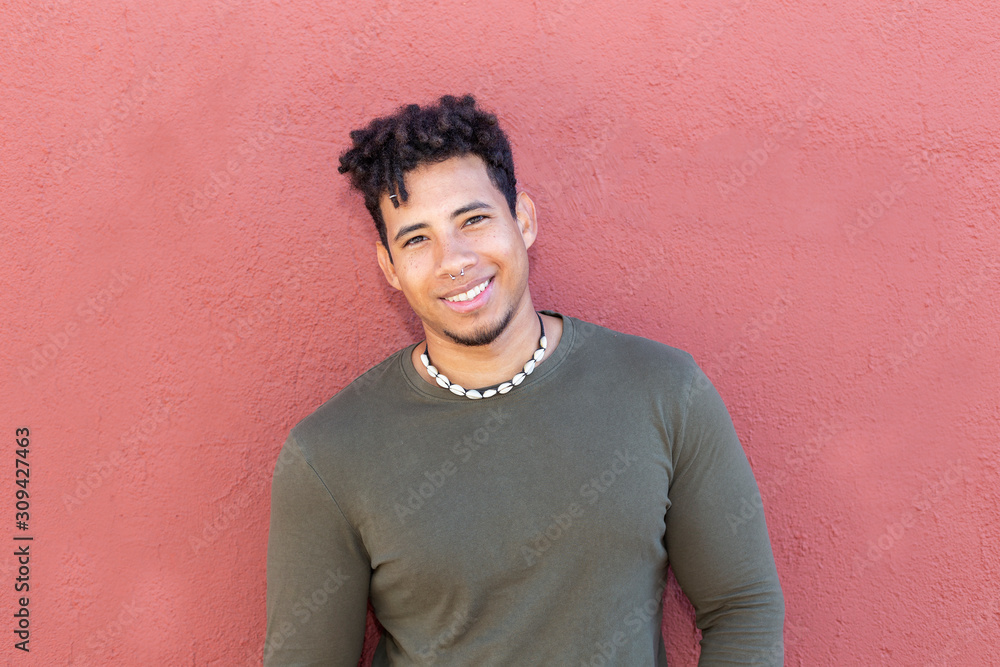 Young boy with curly brown hair and strong body structure, with his back resting on a purple wall and wearing green shirt and jeans. Young boy with curly brown hair and strong body structure, with his back resting on a purple wall and wearing green shirt and jeans.
