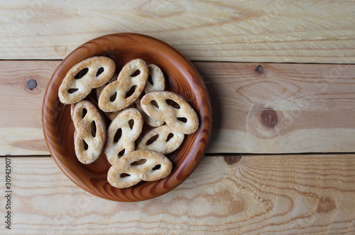 Flat lay view of a wooden bowl filled with 'krakeling' a very popular sort of Dutch cookie. Wooden table background and copy space to the right.