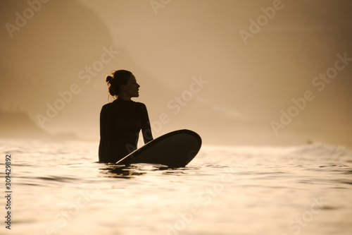 Silhouette of a surfer girl in the waters