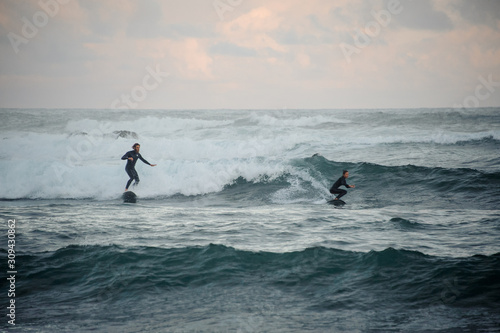 Man and woman riding waves on surfboard
