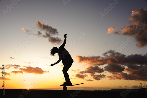 Silhouette of a guy standing on a balance board