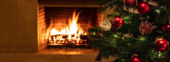 Christmas tree close up on burning fireplace background
