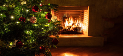 Christmas tree close up on burning fireplace background