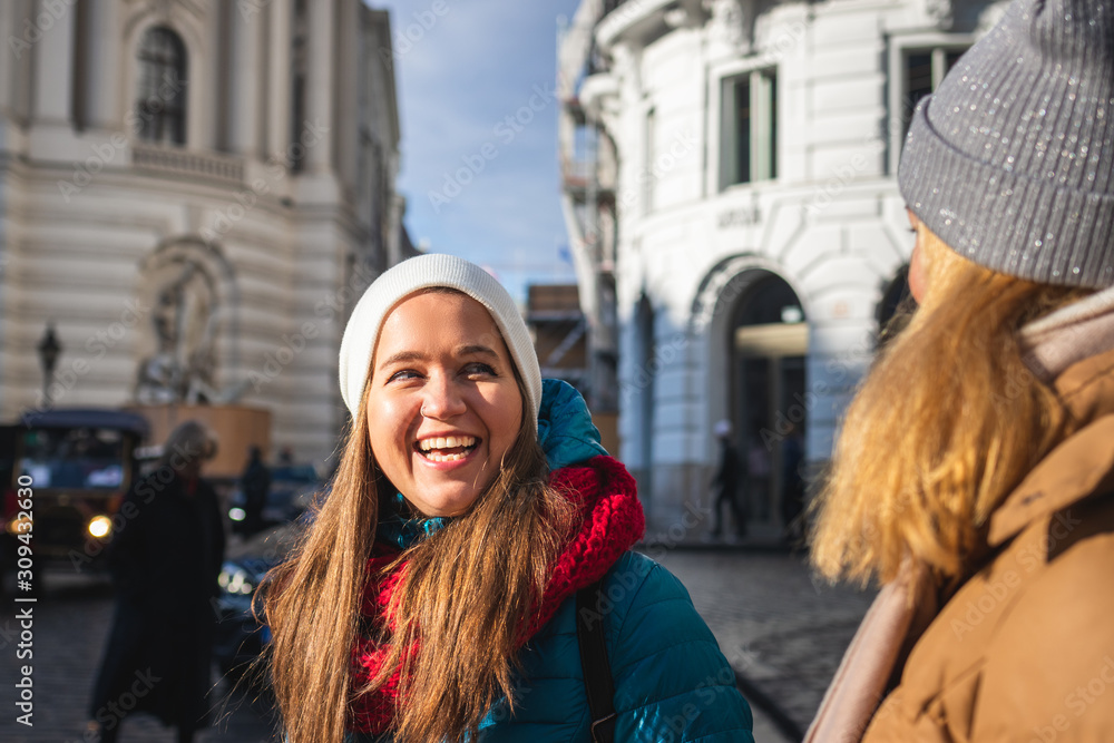 Two women having fun at city during vacation in Vienna, Austria. Young laughing woman and her friend near Hofburg complex
