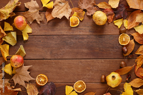 rustic fall background of autumn leaves and chestnuts over barn wood background