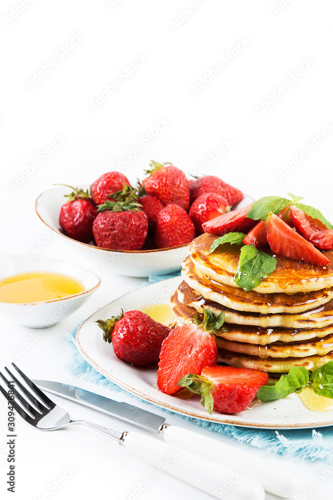 American pancakes lined with strawberries and honey poured on a white background. Classic American Breakfast. American pancakes lined with strawberries and honey poured on a white background. Classic American Breakfast.