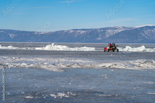red car on lake ice and frozen mountain view