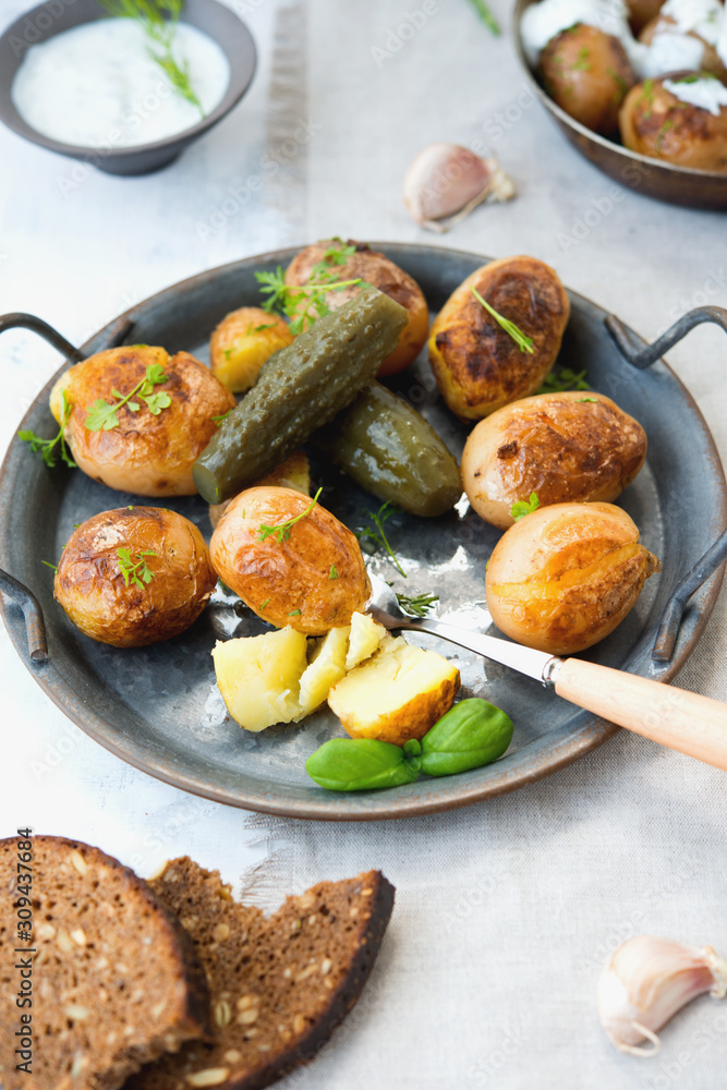 Classic Russian dish baked potatoes with sour cream and herbs and pickles. Vertical photo.