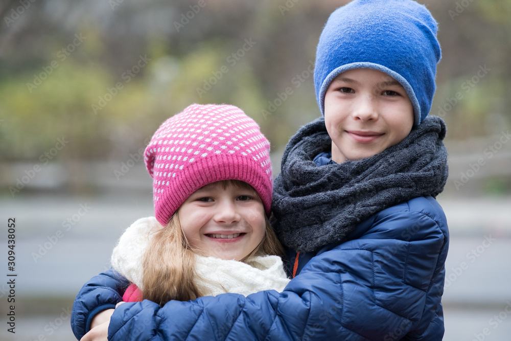 Two children boy and girl hugging each other outdoors wearing warm clothes in cold autumn or winter weather. Two children boy and girl hugging each other outdoors wearing warm clothes in cold autumn or winter weather.