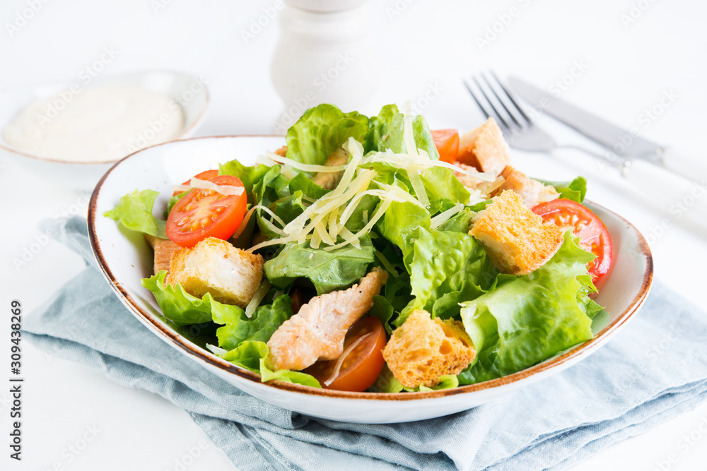Caesar salad with chicken breast, tomatoes and wheat croutons in a plate on a white background. Horizontal photo. Caesar salad with chicken breast, tomatoes and wheat croutons in a plate on a white background. Horizontal photo.