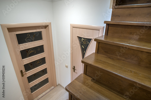 Interior of a house or appartment hallway with oak wooden stairs and room doors.