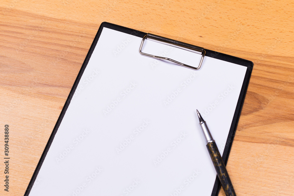 pen on blank white document sheet on wood clipboard on white wood table top view space pen on blank white document sheet on wood clipboard on white wood table top view space