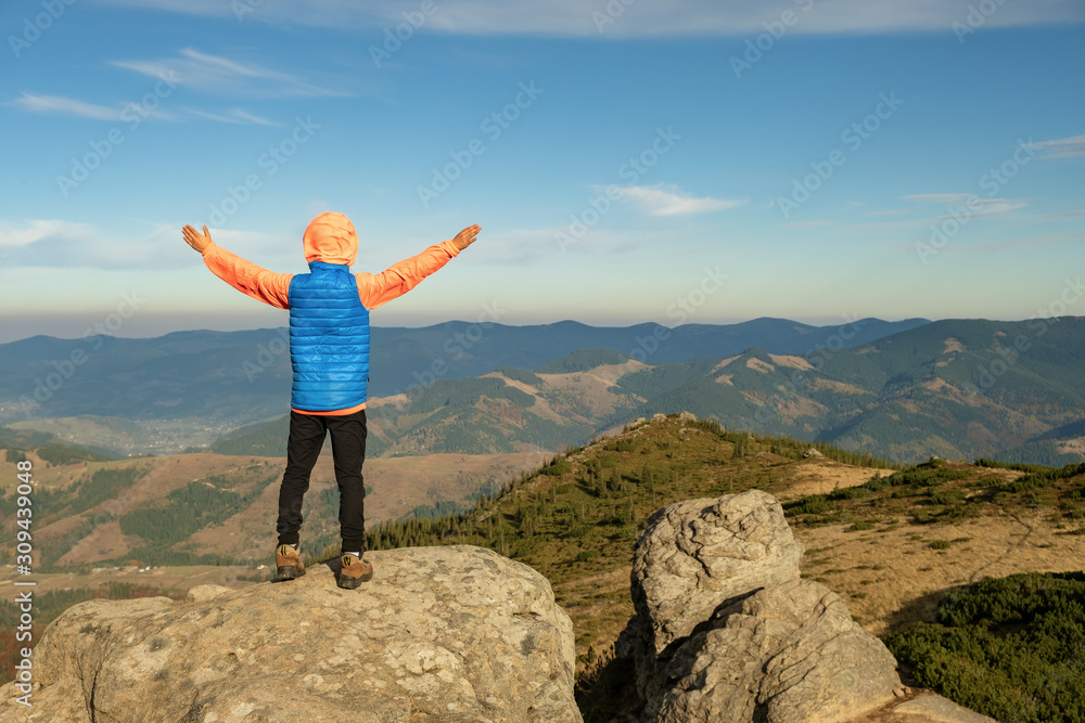 Young child boy hiker standing with raised hands in mountains enjoying view of amazing mountain landscape at sunset. Young child boy hiker standing with raised hands in mountains enjoying view of amazing mountain landscape at sunset.