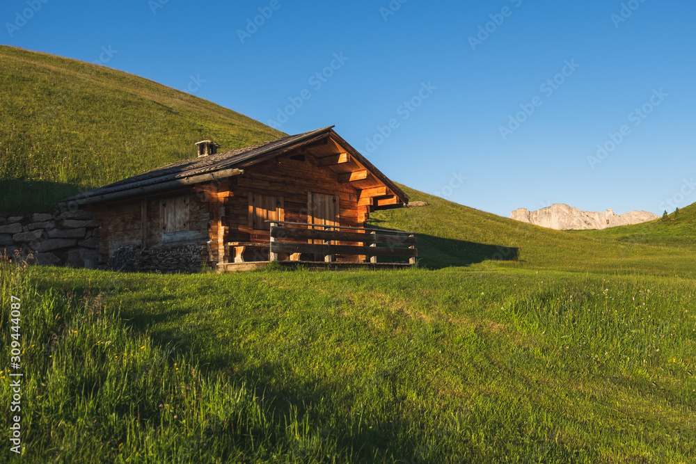 Wooden mountain hut in a green hill during sunset Wooden mountain hut in a green hill during sunset