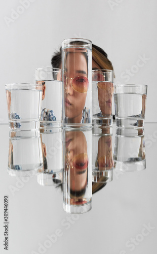 Portrait of woman wearing sunglasses distorted through glasses with water photo