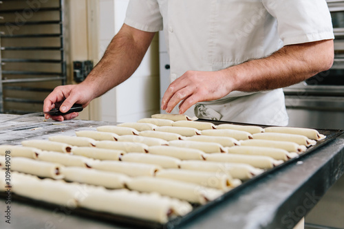 Anonymous hands placing uncooked pastries onto oven tray