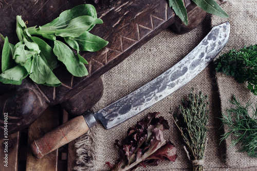 Big vintage knife surrounded by lettuce and other herbs