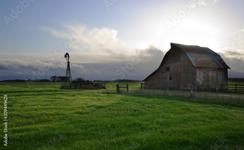 old barn in the green field with windmill