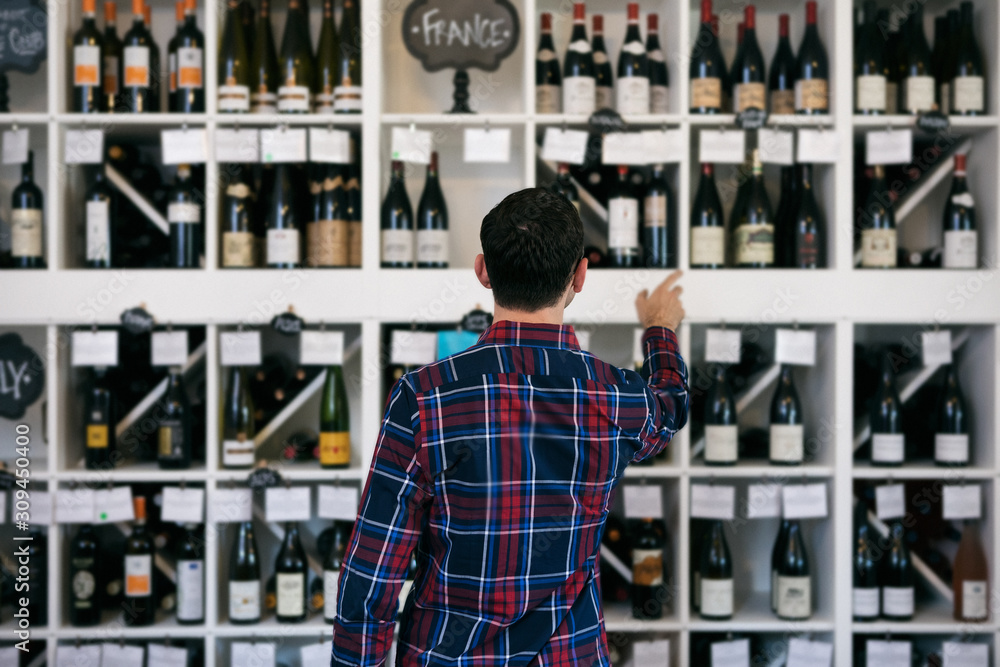Wine: Man Stands In Front Of Wall Of Wine Choices Wine: Man Stands In Front Of Wall Of Wine Choices