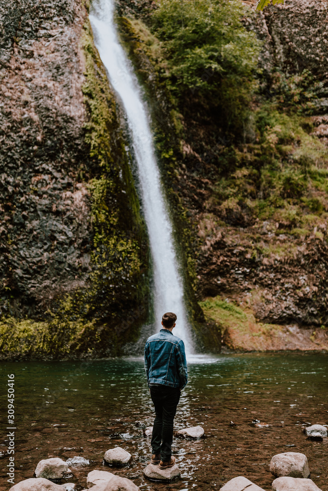 Man on rocks admiring a waterfall Man on rocks admiring a waterfall