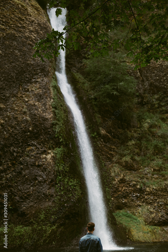 Male looking at stream of waterfall Male looking at stream of waterfall