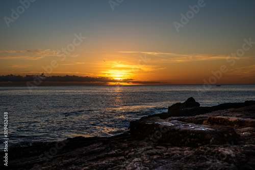 Sunrise over the sea. Rocks on the first plan