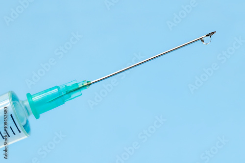 Syringe with medication for injection on blue background. Close up medication needle. Medical concept, flu shot vaccine