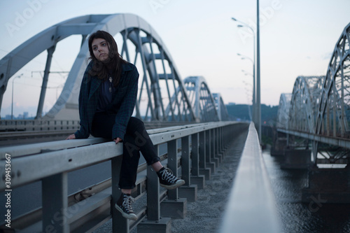 girl sitting on the railing on the background of the bridge photo