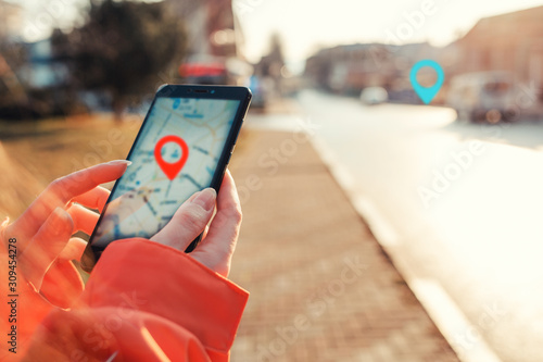 Concept of Internet maps and navigation. Female hands hold smartphone with maps app, and marked location icon, red and blue destination icon photo