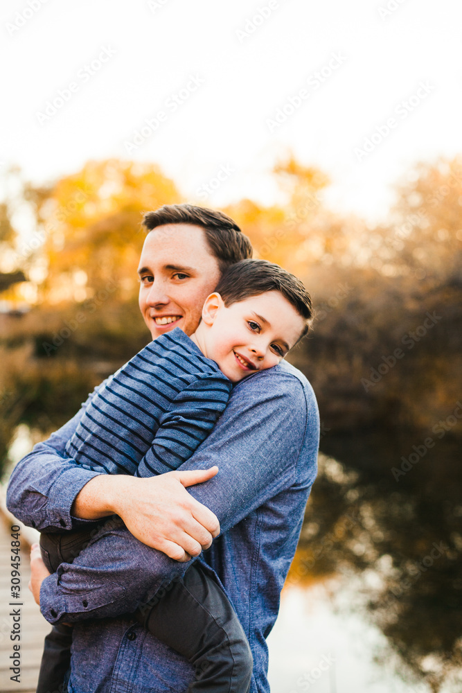 Father holding son with pond behind and sun smiling at camera. Father holding son with pond behind and sun smiling at camera.