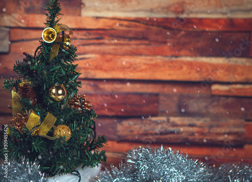 New Year and Christmas-decorated fir tree and beautiful toys with tinsel with snow on a wooden background