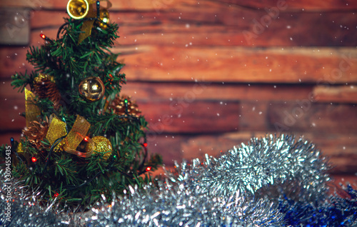 New Year and Christmas-decorated fir tree and beautiful toys with tinsel with snow on a wooden background