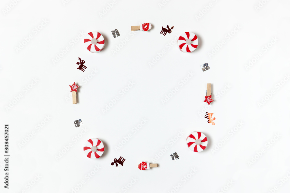 Simple Christmas composition. Round frame of clothespins, candy-bulbs, deer confetti and gifts on white background, copy space. Horizontal. Minimal style. Top view. For social media, greeting card