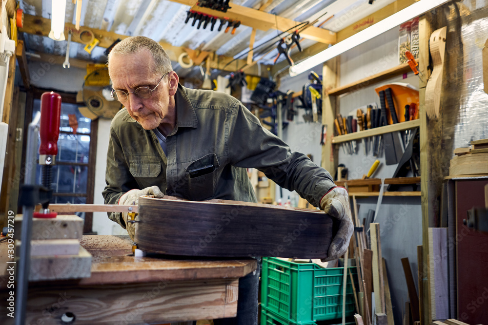 craftsman making a guitar in his woodwork workshop craftsman making a guitar in his woodwork workshop