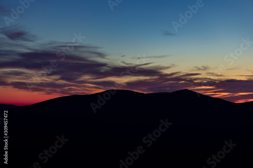 atmospheric natural wallpaper poster photography of mountain silhouette on cloudy twilight sky background after sunset, empty copy space
