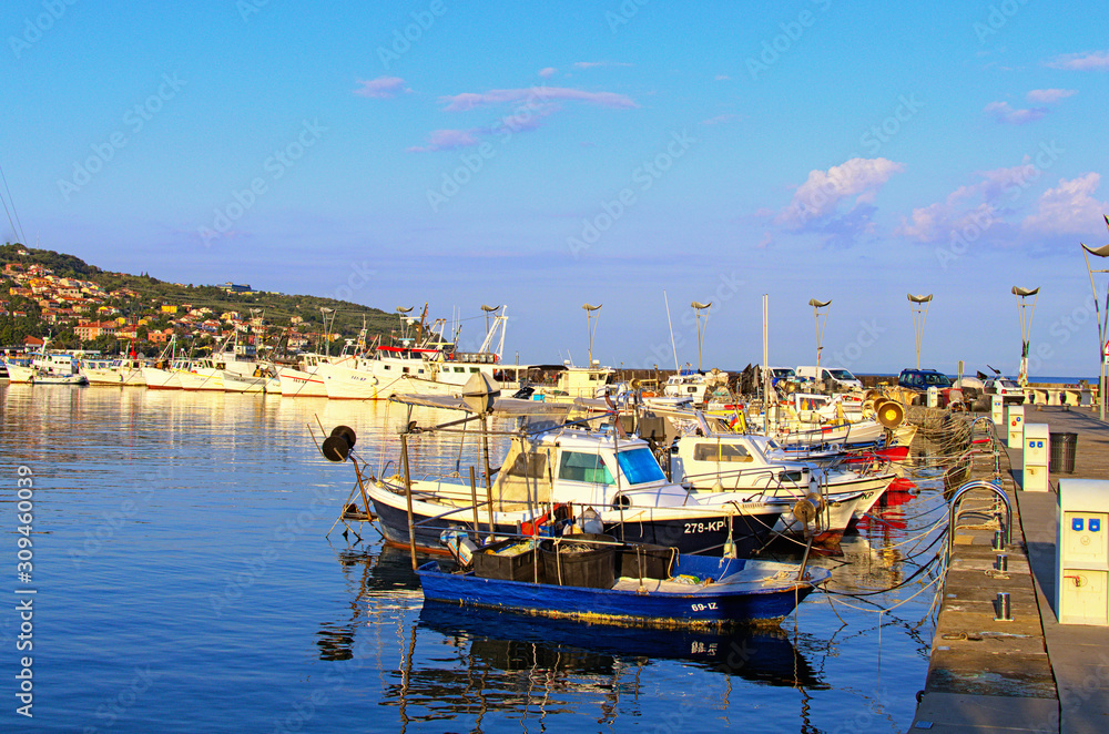 Koper, Slovenia-September 29, 2019: Moored fishing boats in harbor of Koper. Mooring of the small fishing vessel at the dock. Fishing gear and equipment on the boat. Autumn morning landscape