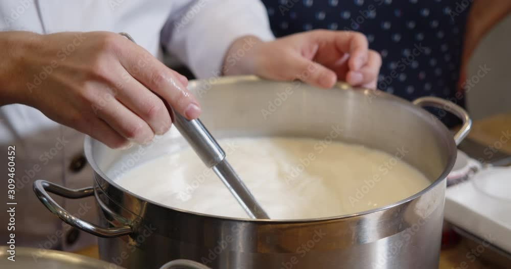 The cook heats and stirs the milk in a saucepan. The cook heats and stirs the milk in a saucepan.