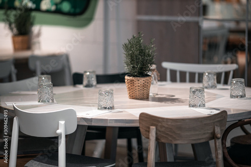 beautifully laid tables with glasses and appliances at night in restauran with blur background